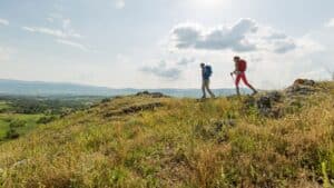 a couple hiking with views of rolling green hills in the background