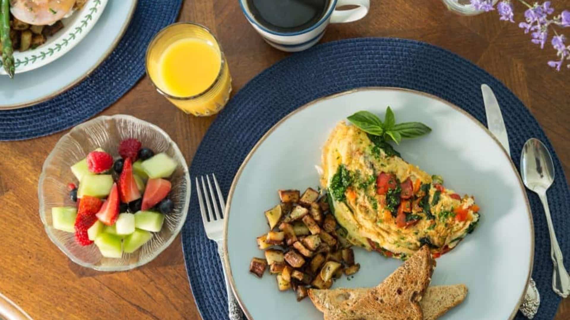 a plate of potatoes, toast, and an omelet with a side of fruit, orange juice, and coffee at devonfield inn