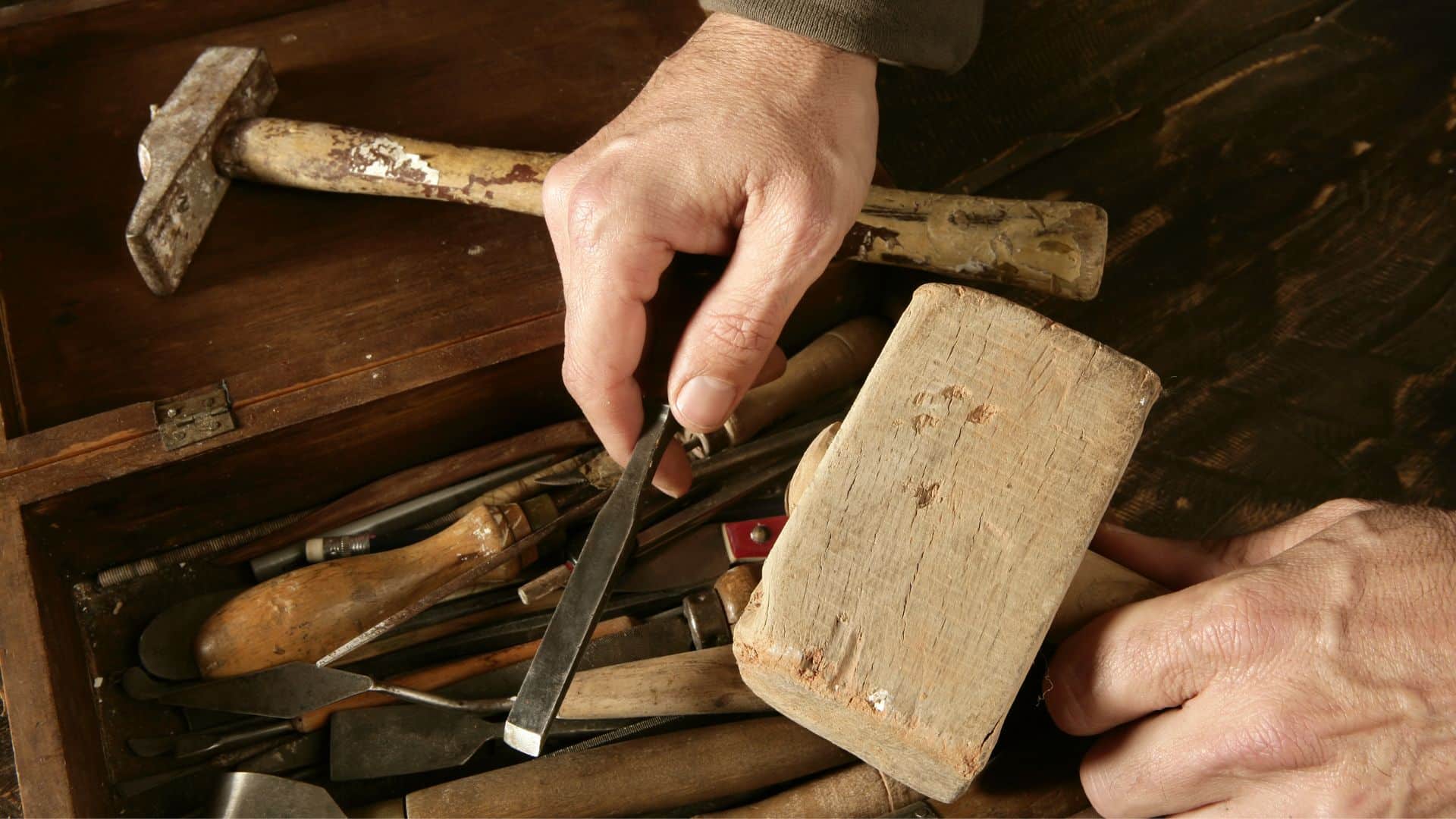 hand woodworking tools on a table with man holding one of them