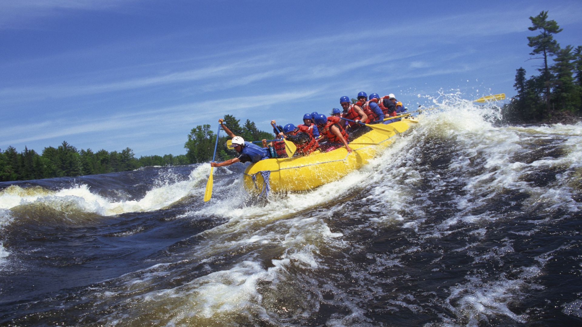 a group of people whitewater rafting in a yellow raft